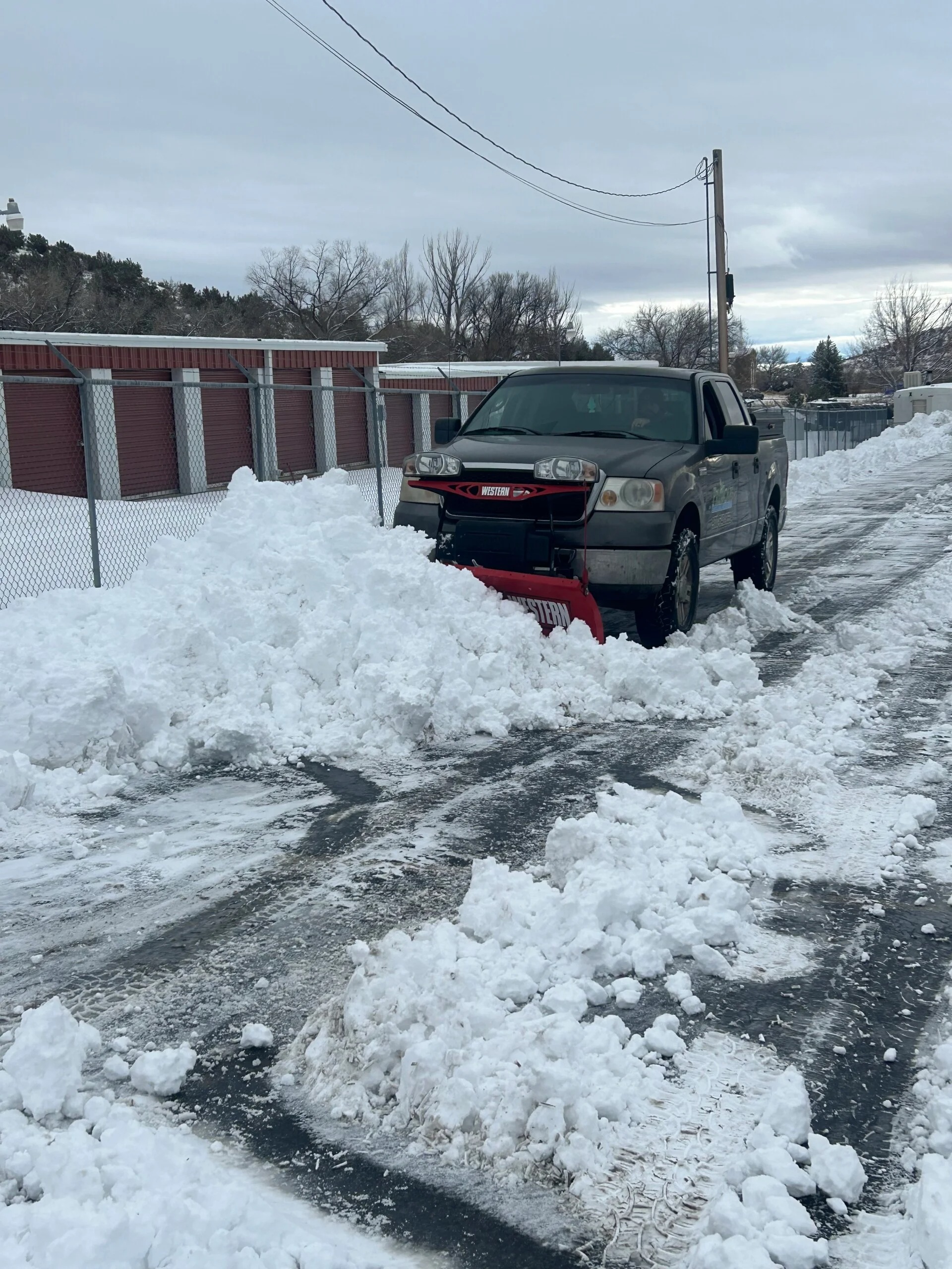 ProScape truck with plow clearing snow from a commercial lot
